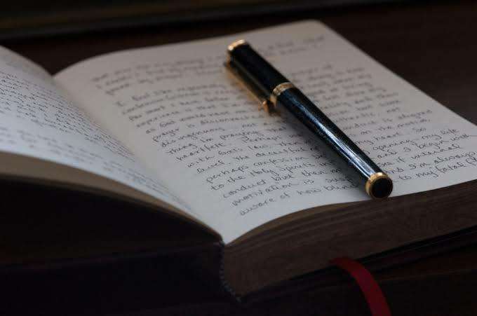 Open journal with self discovery poetry prompts written by hand

